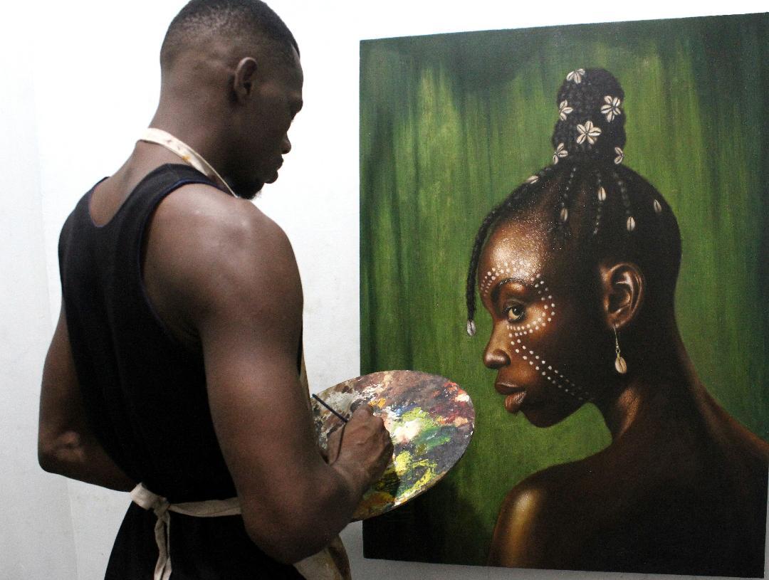 Arinze Stephen Ekwuide painting in his studio